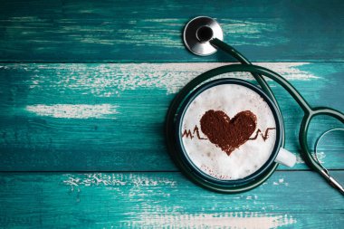 Dünya Sağlık Günü. Kahve aşığı ve kalp hastalığı konsepti için sağlık hizmeti. Tarçın 'dan Latte Art, Top on Heart Shape ve Pulse Beat Rate. Stetoskop içinde sıcak kahve fincanı var. Üst Görünüm