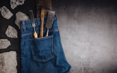 Erkek giysileri, Baba ve İşçi Bayramı konsepti. Babama bir hediye. Deri Ayakkabılar, Beton ve Tamirci Aletleri ile çevrili kot pantolonlar çimento zemininde yatıyordu. Koyu ton