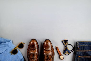 Erkek giysileri, Babalar Günü konsepti. Klasik stil. Açık Gri Arkaplanda Düz Yerde. Ayakkabı, el saati, papyon, gömlek, kot pantolon ve güneş gözlüğü dahil. Tarz sahibi erkekler. Üst Görünüm