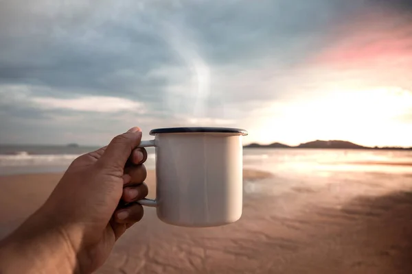 モーニングコーヒー 日の出の間にビーチでホットコーヒーを飲む お気に入りのドリンクや自然を楽しむためにカップを開催手 新しい一日を始めなさい リラックスし 調和のとれた生活ライフスタイル Pov View — ストック写真