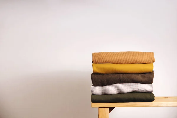 Clothes Concept. Stack of Clothing by the White Wall. Organic Cotton, Earth Tone