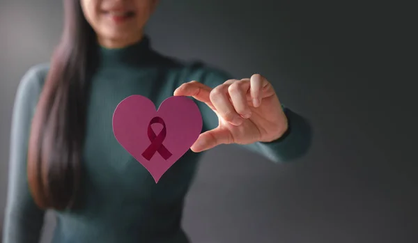 Love, Health Care, Cancer, Donation and Charity Concept. Breast Cancer Awareness. Close up of Smiling Volunteer Woman Holding a Heart Shape with Cancer Ribbon Sign Paper