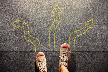 Bir çok çizilmiş okun arasında duran ayaklar, kararı, seçimi, yönü ve yeni bir şeye başlama cesaretini simgeler.