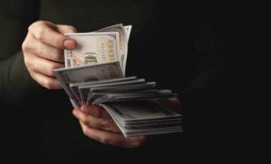 Amerikan dolarlarını sayan eller, finans, ödeme, bankacılık ve ekonomik işlemleri sembolize ediyor. Yakın plan Ön plan