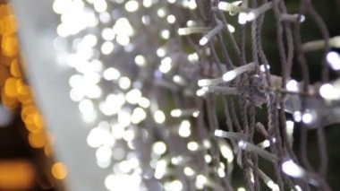 LED ampullü bir caddenin dekorasyonu el kameralı bir video. Mutlu yıllar ve Xmas teması. Bulanık, pırıl pırıl çelenk ışıkları, soyut bulanık arkaplan. Alanın derinliği, odak değişimi.