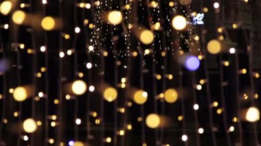 Noel ve Yeni Yıl tatili aydınlatması şehir sokaklarında gece vakti. Altın parıltı ve sallanan çelenkler ve Xmas yıldızı süslendi. Yanıp sönen ışıklar, parlayan sihirli toz