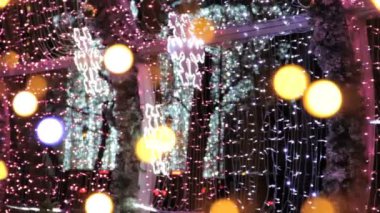 Noel sokak süslemeleri, yeni yıl hazırlıkları. Işık titreşimi ve parlak kar taneleri. Dev ışık tünelinde parıldayan çelenkler.