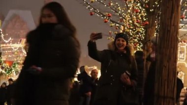 MOSCOW, RUSSIA - 21 Aralık 2017: Moskova 'daki Kızıl Meydan yakınlarında Noel pazarında insanlar. İnsanlar fotoğraf çeker ve eğlenir, parlak ışıklar arka planda bulanık çekim yapar.
