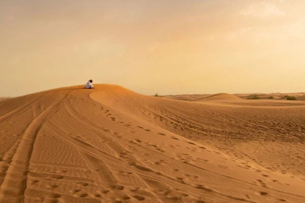 Foto de un residente local rezando en una duna de un desierto en la Uni Imágenes de stock libres de derechos