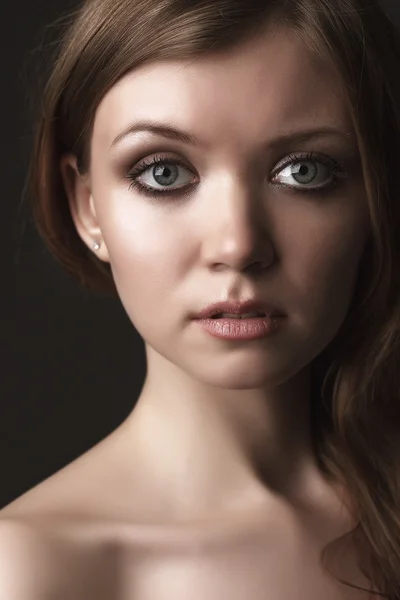 Porträtt av den vackra unga flickan på en mörk bakgrund. ansikte — Stockfoto