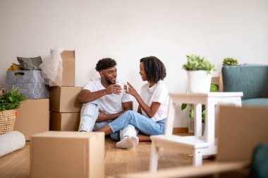 Yerde oturan çift gülümseyen kutularla çevrili.