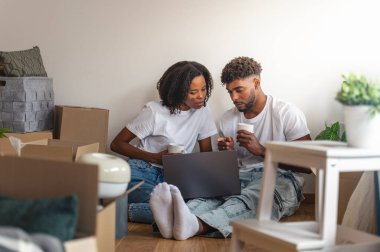 Bir çift yerde oturmuş birlikte dizüstü bilgisayara bakıyor.