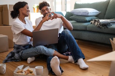 Birlikte oturan çift ellerle kalp şekli oluşturuyor.