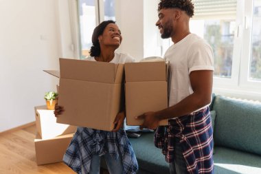 Oturma odasında karton kutular tutarken gülümseyen bir çift.