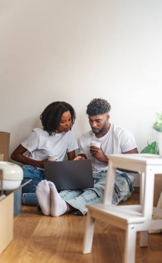 İki kişi dizüstü bilgisayar kullanarak yerde oturuyor.