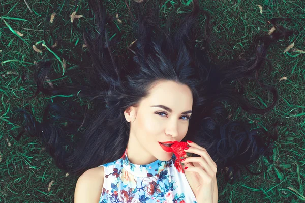 Menina bonita com morango na boca — Fotografia de Stock