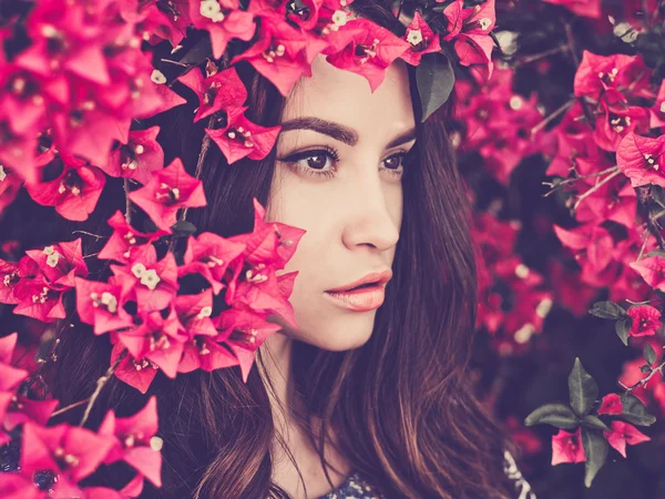 Belle jeune femme entourée de fleurs — Photo