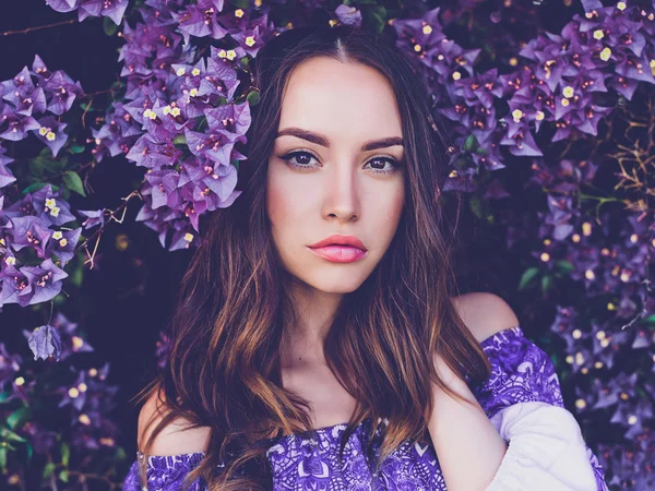 Vacker ung kvinna omgiven av blommor — Stockfoto