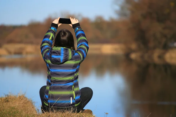 Молода дівчина використовує свій мобільний телефон для створення фотографій — стокове фото