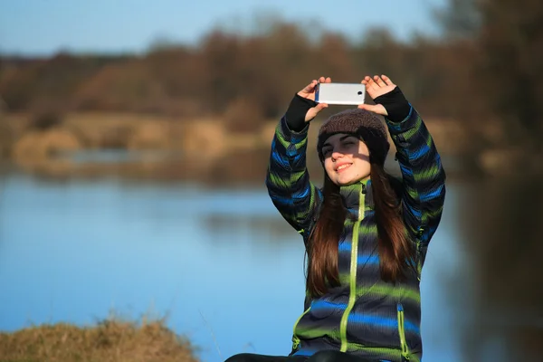 Молодая девушка использует свой мобильный телефон для фотографирования — стоковое фото