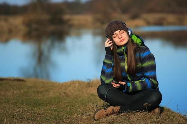 Jovem sentada no chão e ouvindo música após a caminhada — Fotografia de Stock