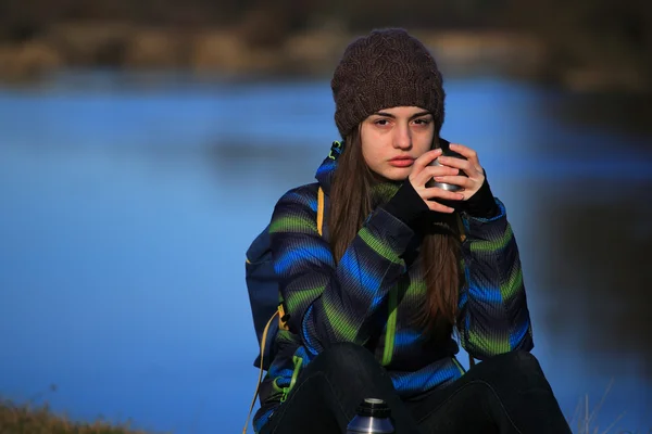 Girl sitting on the ground and drink tea after hike — Stock Photo, Image