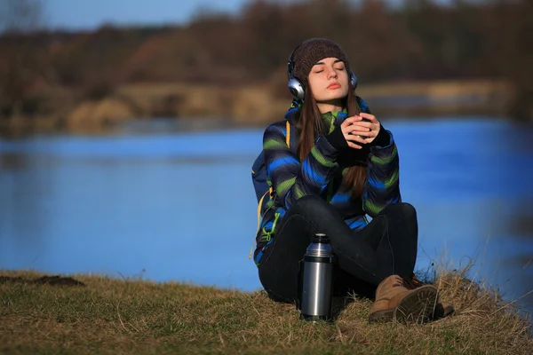 Chica joven sentada en el suelo y escuchando música después de la caminata —  Fotos de Stock