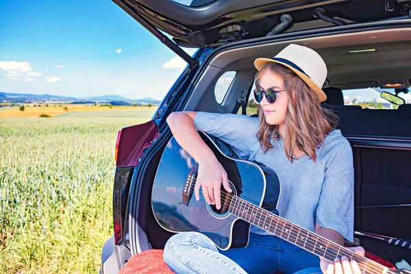 田舎の旅で車の中にギターを入れた若い女の子が — ストック写真