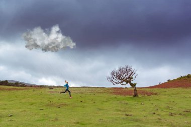 Bir kız, yaylada defne ağaçlarıyla koşuyor.