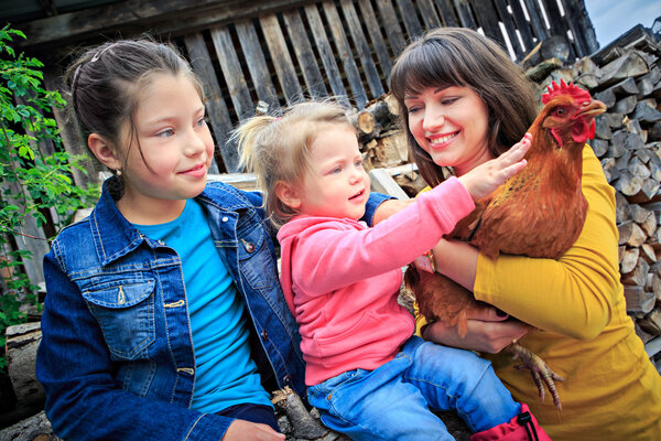 Mother with daughters holding chicken