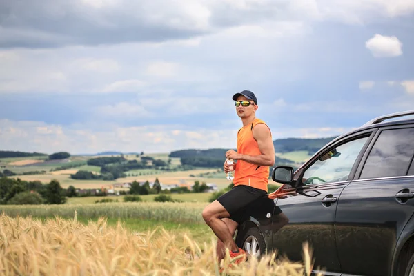 Homme debout près de la voiture dans le champ Images De Stock Libres De Droits