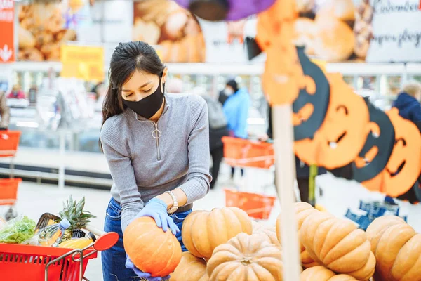 Молодая Женщина Защитной Маске Перчатках Выбирает Тыквы Хэллоуин Супермаркете Реальность — стоковое фото