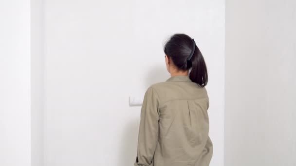 年轻女子用滚筒在墙上画画 从后面看 自行整修和新的住房概念 复制空间 — 图库视频影像