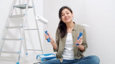 Genç, gülümseyen bir kadının portresi boya silindirleri hakkında konuşuyor ve video bloğu için bir video kaydediyor. Bloglama, sosyal medya ve yenileme kavramı