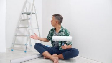 Genç gülümseyen bir adamın portresi boya silindirleri ve video kaydı hakkında konuşuyor. Bloglama, sosyal medya ve yenileme kavramı