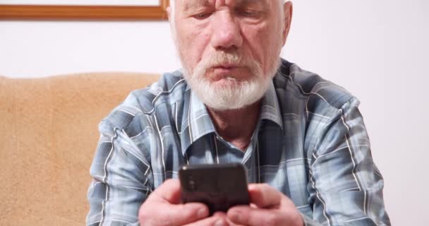 Odaklanmış Yaşlıların Elinde Mobil Teknolojiyi Öğrenen Bir Adam Kanepede Oturmuş — Stok video