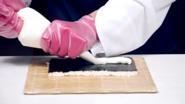 Mutfakta suşi pişirirken eldivenli aşçıların ellerini kapat..