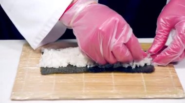 Mutfakta suşi pişirirken eldivenli aşçıların ellerini kapat..