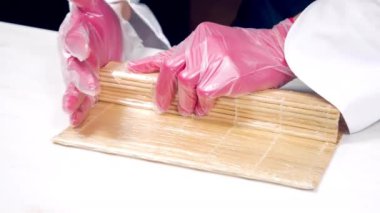 Mutfakta suşi pişirirken eldivenli aşçıların ellerini kapat..