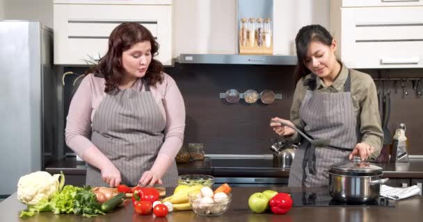 Två attraktiva unga kvinnor laga middag av färska grönsaker i köket — Stockvideo