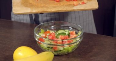 Masanın üzerinde taze sebze salatası olan bir kasenin yakın çekimi. Sağlıklı gıda hazırlama süreci.