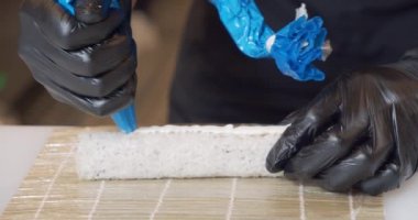 Mutfakta suşi pişirirken eldivenli aşçı erkek ellerini kapat..