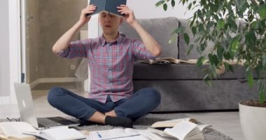 Yorgun genç bir adam kafasına kitap geçirir ve ders kitaplarının arasında meditasyon yapar. Öğrenme sırasında stres hisseder ya da evde yerde otururken uzaktan çalışırdı..