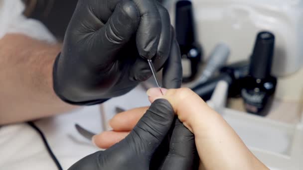 Close-up van de handen van een meester in zwarte handschoenen aanbrengen gel polish op de nagels van een klant in een schoonheidssalon. Manicure-proces. — Stockvideo