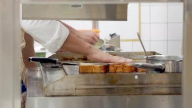 Erkek şefin elleri mutfakta ekmek kızartırken yakın plan çekimi. Restoranda sandviç yapıyorum.