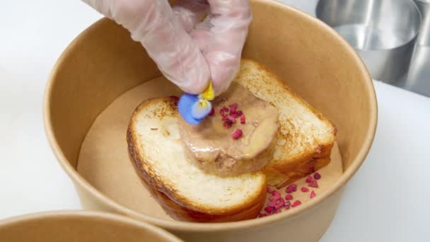 Gros plan de délicieux toasts à la crème, de baies lyophilisées et d'une fleur dans un bol artisanal. Cuisine moléculaire ou fusion. — Video