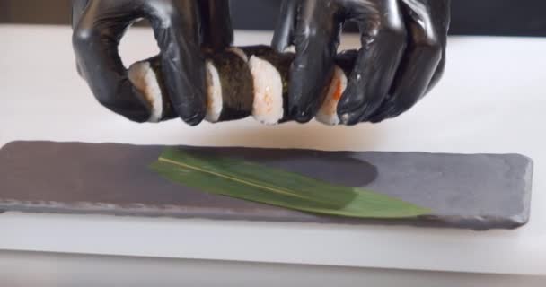 Close-up shot van een chef-kok handen in handschoenen leggen heerlijke sushi broodjes met krab vlees op een bord — Stockvideo