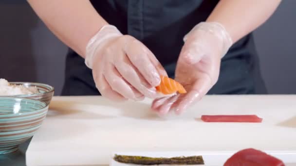 Primo piano mani maschili di cuoco in guanti mettendo sashimi con salmone su un piatto. — Video Stock