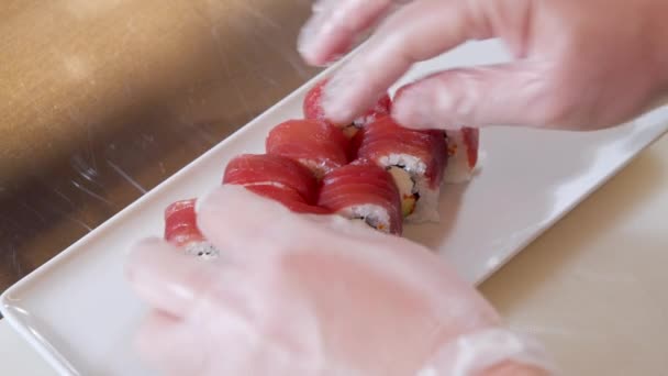 Close-up van mannelijke chef-kok handen in handschoenen bereiden van heerlijke sushi broodjes met tonijn in de keuken — Stockvideo