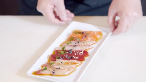 Close-up van mannelijke chef-kok handen in handschoenen serveren heerlijke voorgerecht van verse vis en inktvis met truffel saus en kruiden op een bord — Stockvideo